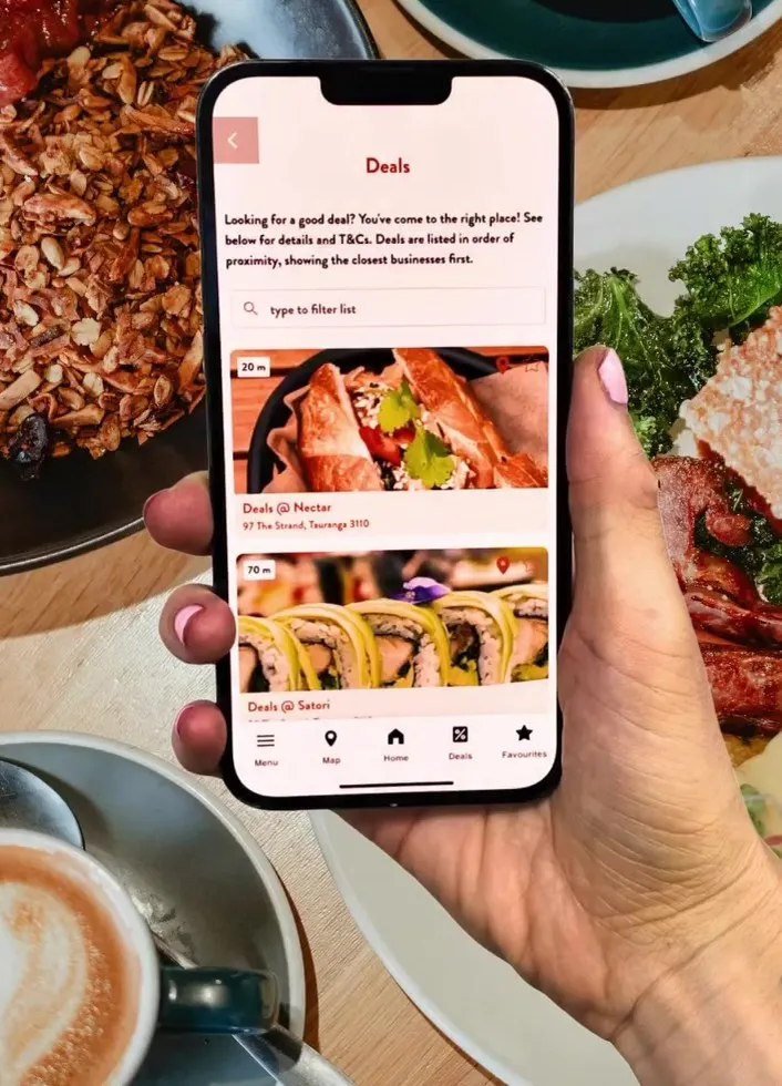 Deals screen listing local food deals, held over a café table